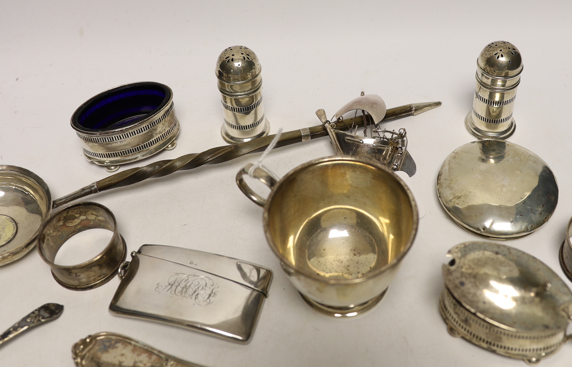 A 1930's silver single handled cup, a four piece silver condiment set, Edwardian silver card case, pair of silver pepperettes, napkin rings, sundry small flatware including sterling etc.